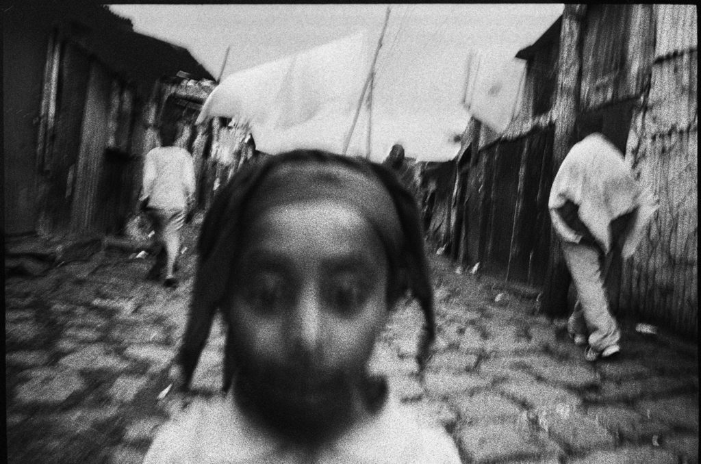 Photographie argentique en noir et blanc d'une tête de petite fille dans rue pavée du Mercato à Addis Abeba/Ethiopie.