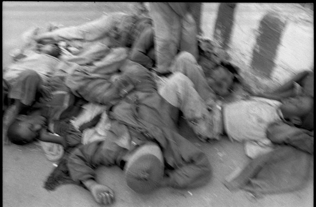 Photographie argentique en noir et blanc d'enfants de la rue dormant enchevêtrés sur le bitume à Harar/Ethiopie.