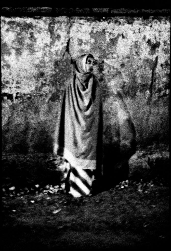Photographie argentique en noir et blanc d'une femme se tenant debout sur la Churchil Road à Addis Abeba/Ethiopie.