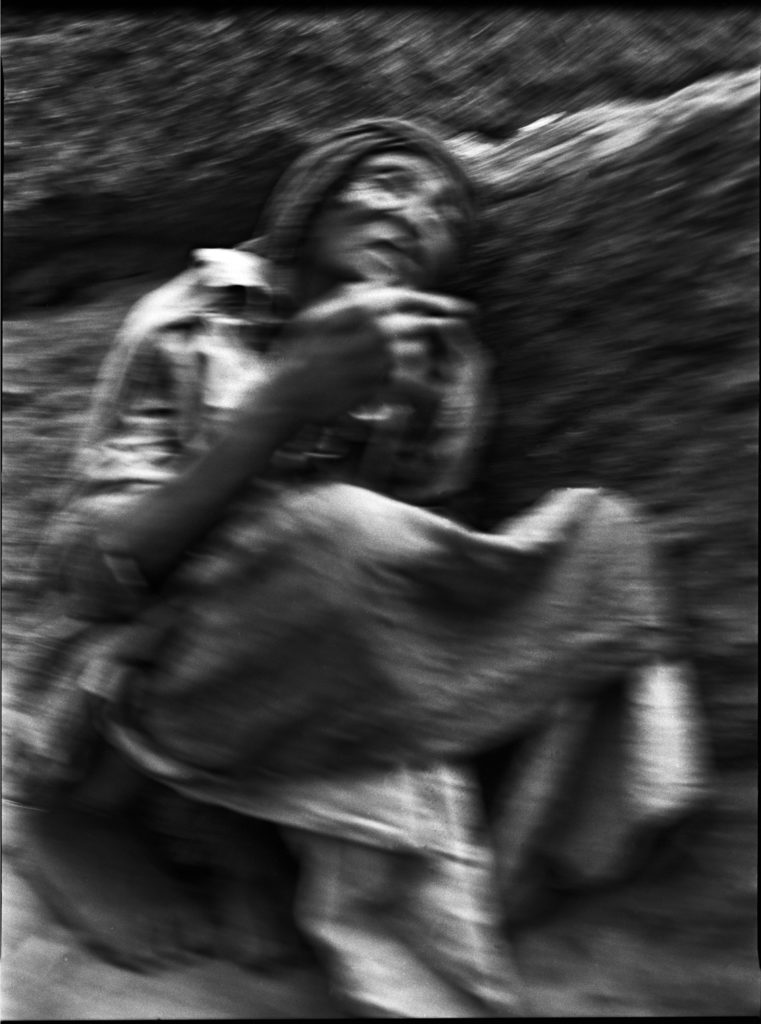 Photographie argentique en noir et blanc d'une femme en prière assise tout contre un rocher à Lalibela/Ethiopie.