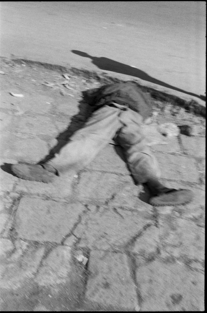 Photo argentique en noir et blanc d'un corps gisant à terre et couronné par une ombre humaine de passage à Addis Abeba/Ethiopie.