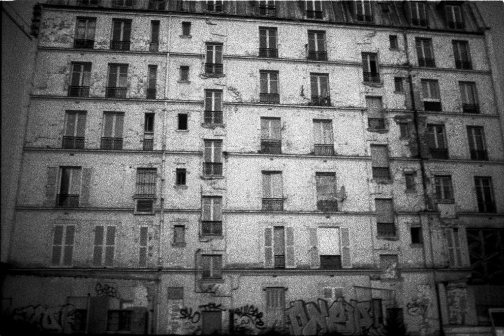 Photographie argentique en noir et blanc d'une façade d'immeuble dans la rue Philippe de Girard à Paris.