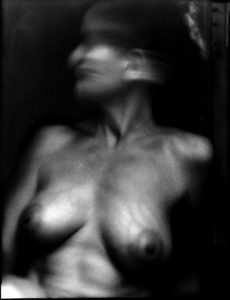 Photographie argentique en noir et blanc d'une femme aux seins nus.