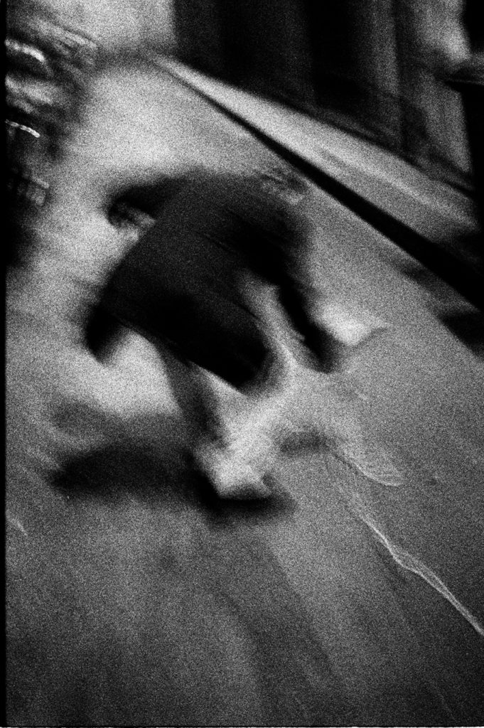 Photographie argentique en noir et blanc d'un homme seul dans une rue de Paris et s'abaissant vers le sol.