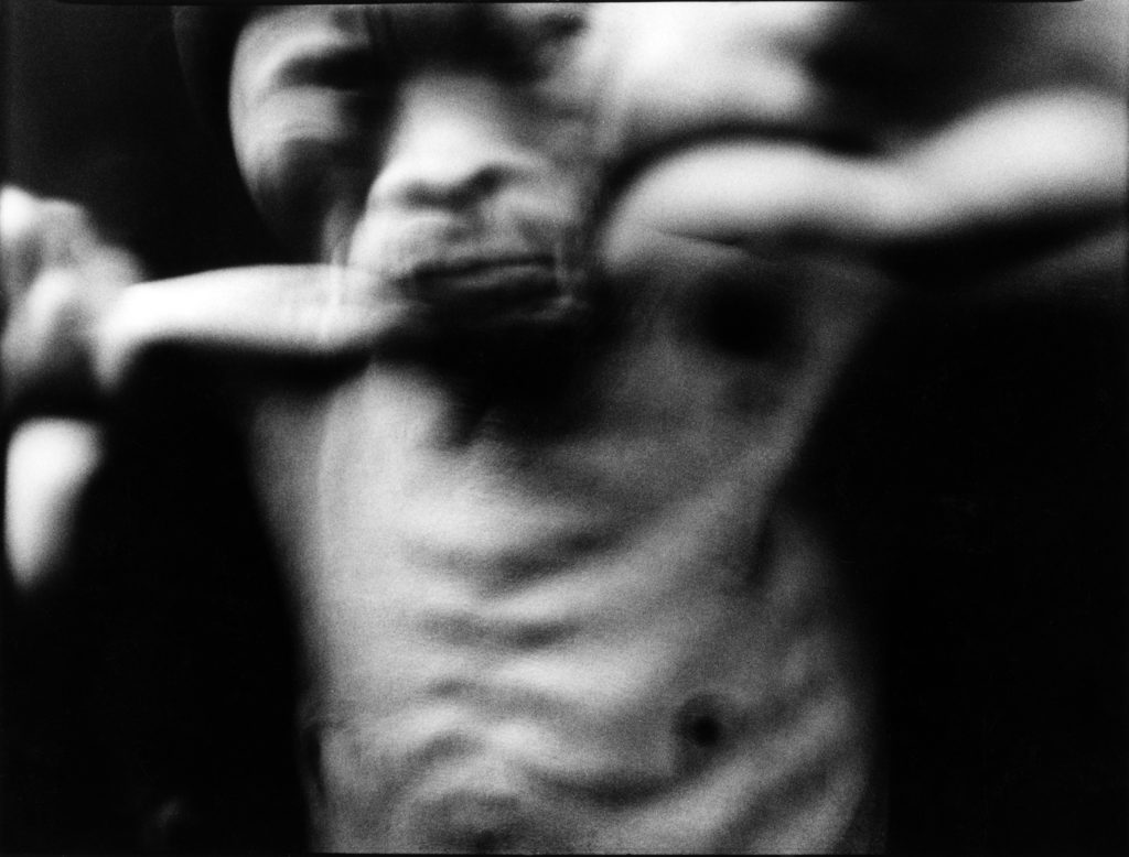 Homme torse nu à la face simiesque.