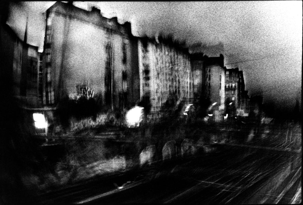 Photographie argentique en noir et blanc d'immeubles au bord de voies ferrées dans le quartier de la gare du Nord à Paris.