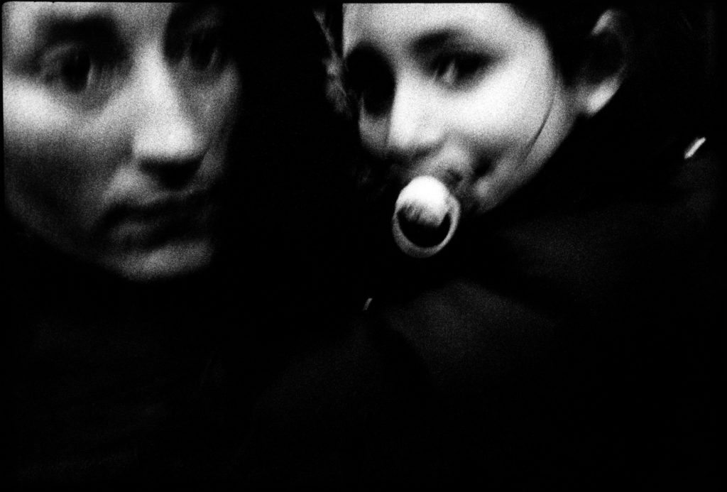 Photographie argentique en noir et blanc des visages d'une femme et de son enfant dans une rue du Marais à Paris en 2002.