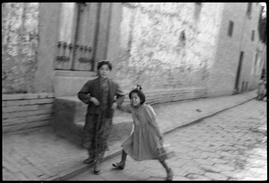 Photographie argentique en noir et blanc de 2 jeunes filles ouïgours se tenant par la main dans une rue de Kashgar en Chine en 1997.