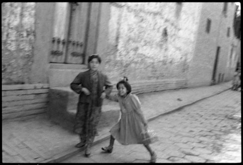 Photographie argentique en noir et blanc de 2 jeunes filles ouïgours se tenant par la main dans une rue de Kashgar en Chine en 1997.