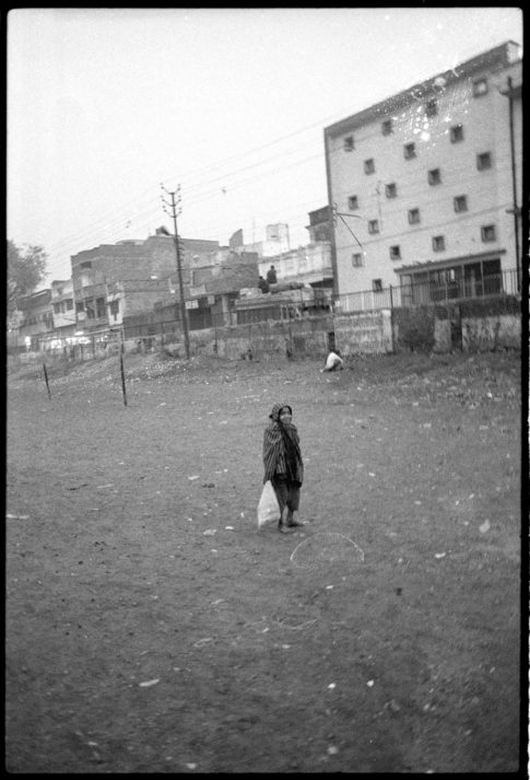 Photographie argentique en noir et blanc d'une personne mi femme mi enfant dans un terrain vague à Bénarès/Inde.