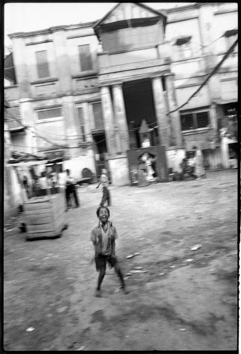 Photographie argentique en noir et blanc d'un jeune garçon criant dans une cour de Calcutta en Inde.