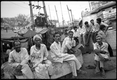 Photographie argentique en noir et blanc d'hommes assis dans un quartier populaire de Delhi/Inde.